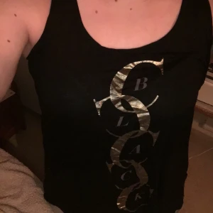 Linne  - Svart linne med guldigt tryck. Köper man fler plagg så kan jag skicka det i samma paket om det önskas 