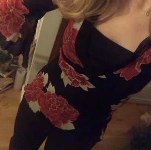 Rödblommig topp - Säljer denna fina topp pga av att den inte kommer till användning längre. Man knyter den i ryggen som ni kan se på andra bilden. Väldigt fina ärmar!! Jättebra skick