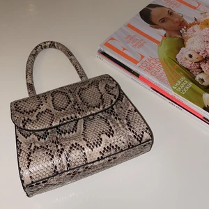 Handväska - Handväska i imiterad ormskinn från Nelly, helt slutsåld. Liten och behändig väska som också är väldigt snygg. Den är bara använd en gång så den är som ny. 