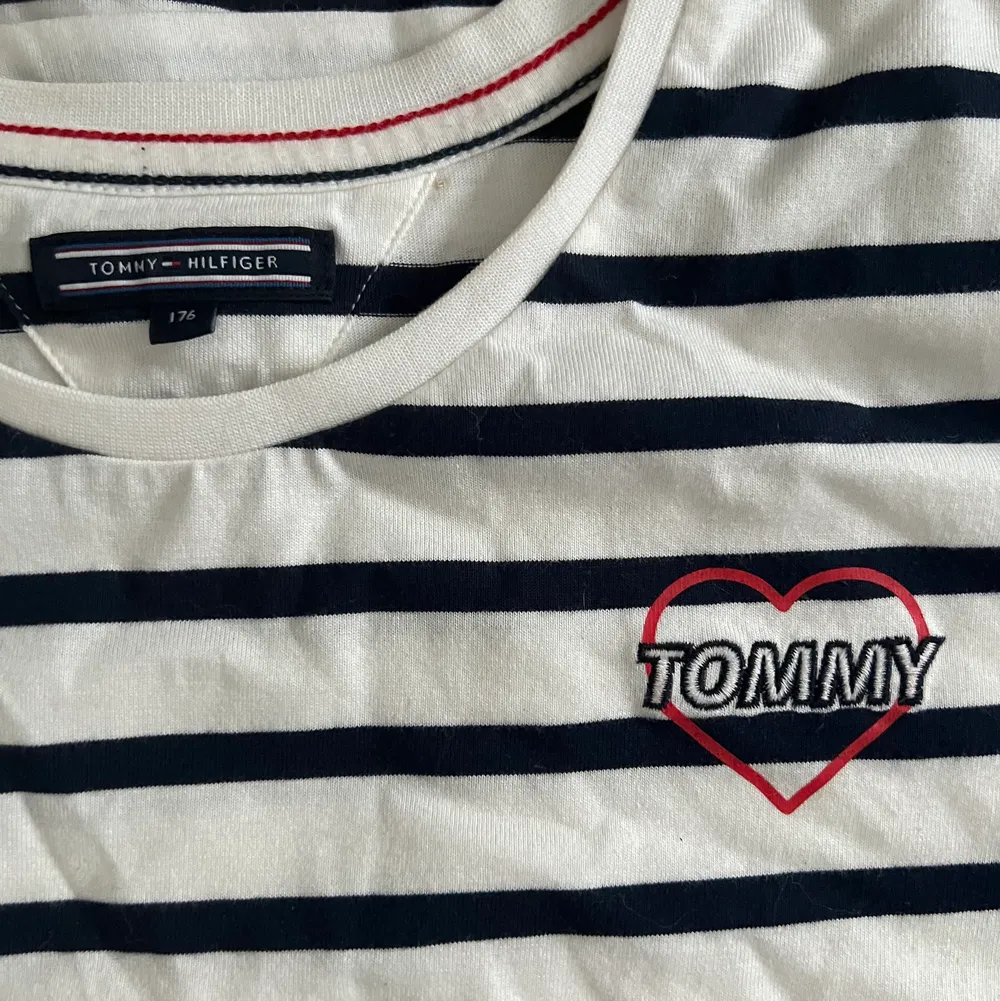 Säljes Tommy Hilfiger t-shirt, vit med marin blå ränder. Stl 176 barn men passar mig som har S i kläder. 100kr eller bud. I nyskick! . T-shirts.