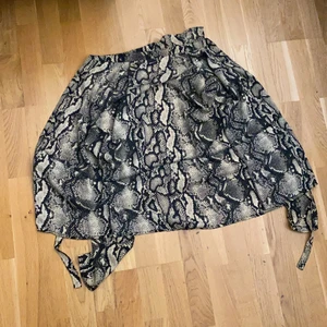 En öppen skjorta, storlek 34 - En öppen mönstrad skjorta i storlek 34 köpt från gina tricot. Använd 1 gång för ca 2/3 år sen. Knappar på framsidan men även band som kan knytas. En skjortkrage. 