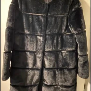 Neo Noir kappa i stl. S. Ny! - Jättefin kappa från Neo Noir. Rak, enkel i passform med markerade ränder som ger en fin och lyxig siluett. Rund hals samt försluts med dolda kryckknappar.                         Material: 100% Polyester , Färg: svart. 