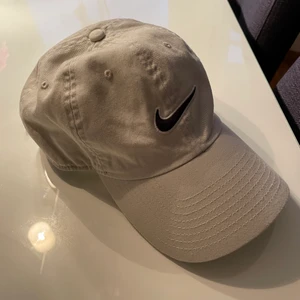 Nike keps beige onesize - Supersnygg och cool keps från Nike i färgen ljusbeige/benvit! Nikemärket på kepsen är mörkblått/svart med vita konturer, och kepsen går att dra åt eller spänna av där bak. Helt oanvänd, så den är i nyskick! Frakt tillkommer.