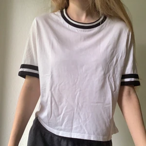 T-shirt  - Vit T-shirt med ränder vid halseingning och ärmslut. Köpt på Forever21 i Japan. Sparsamt använd. Storlek M. Skönt material (50% bomull 50% modal).