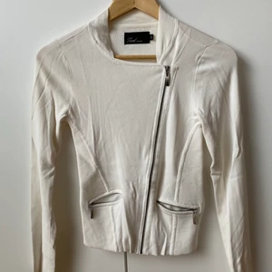 Snygg vit kofta från MQ - Tuff vit kofta med snedplacerad dragkedja från Zoul (MQ). Storlek XS. Material enligt bild. Lite skrynklig men i övrigt hittar jag ingenting att anmärka på.