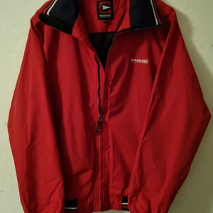 Röd Vindjacka - röd vindjacka i bra skick, använd 2-3 gånger. fungerande dragkedjor och inga trasiga sömmar. perfekt till vår och höst. köparen står för frakt.
