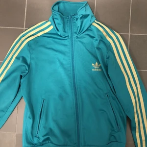 Adidas zip tröja - En turkos adidas jacka/tröja med guld detaljer. Den har bra resår längst ner vilket ger en snygg form. Har använt 2 gånger💥⭐️