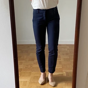 Mörkblå kostymbyxor, stlk S - Mörkblå kostymbyxor från Mango. Sitter snyggt över rumpan,  har pressveck och en lite slits på ca 4 cm på insidan av anklarna. 
