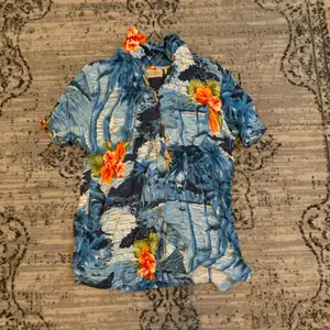 En blå hawaiiskjorta med blommor, och diverse, på. Köpt secondhand för ett drygt år sedan, aldrig använd. 🌊🌼
