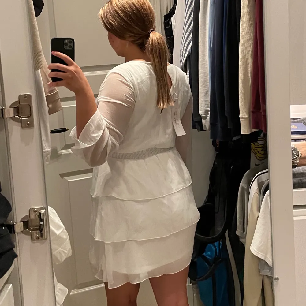 En vit klänning med volanger. Klänningens längd är till mitten av låret på mig som är 168 cm lång. Klänningen har aldrig använts. . Klänningar.