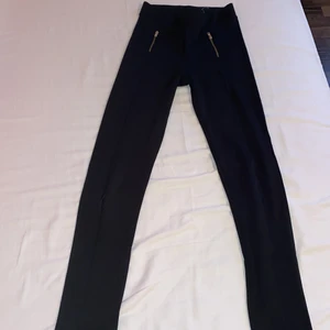 Svarta leggings - Svarta leggings med fin guldig detalj. Lite tjockare material med högre kvalitet än vanliga leggings. Har en svart söm längs vardera ben. Litet hål på höger ben. 