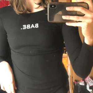 Svart ”babe” body - En svart body som är lite ribbad med texten ”BABE.”   