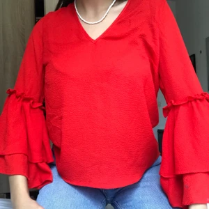 Röd topp med volanger  - Fin röd topp med volanger i stl 42 med öppen rygg och en rosett som man kan fixa lite hur man vill! Har använts bara två gånger. Frakt står man själv för eller så kan man hämta den!