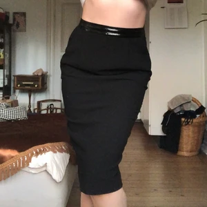 Svart D&G pennkjol - Kjolens motsvarighet till ”den lilla svarta”. Pennkjol märkt D&G (DOLCE&GABBANA). Det matta tyget är stretchigt medan det blanka, skinnliknande tyget sitter fast och markerar midjan. Dragkedja och slits bak. Köpt på humana second hand men aldrig använd.