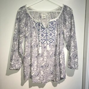 Söt blus med mönster - Blus med snören och stickat mönster i vitt och blått på framsidan. Köpt på H&M. Sparsamt använd.