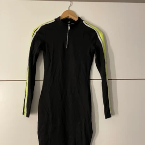 Klänning me detaljer - Säljer denna fina klänning med en tight passform med vita och neon gröna detaljer med en dragkedja vid halsen💚 använd max 4 gånger