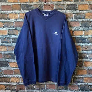 Vintage marinblå Adidas Sweater - Mörkblå v-ringad vintage Sweater från märket Adidas. I superfint skick. Inga hål eller fläckar. Passar som L. Väldigt snyggt oversized med ett par baggyjeans! 🙌