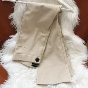 Byxor läderimitation strl: S - Fina beige läderbyxor. Något mer utsvängda. Sparsamt använda. 