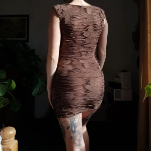 Brun klänning med blommor 🌸🌼 - Härlig retro brun klänning med blommor. 🌸🌸🌼🌸 Blomdetaljer och genomskinliga mesh"slits". Passar XS och XS/S bäst. I begagnat skick.