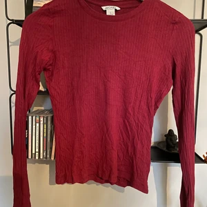 En rödbrun långärmad tröja.  - En tight långärmad T-shirt som passar bra till jeans. 