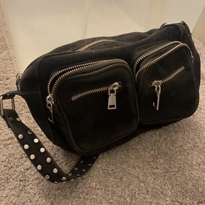 Noella väska  - En svart noella väska med nitar på bandet och dragkedja samt små fickor! Jättefin och finns även ett långt band till den. 200kr+frakt. Hör av dig vid frågor o fler bilder! 
