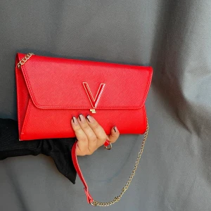 Valentino by mario väska! - Hej! Säljer denna röda brevformade valentinoväskan p.g.a flytt. Älskar verkligen färgen och de guldiga detaljer, kedjan går att ta bort (se bild två). Perfekt väska till en bal, bröllop eller festande. Det finns mycket förvaring så en plånbok behövs ej😍