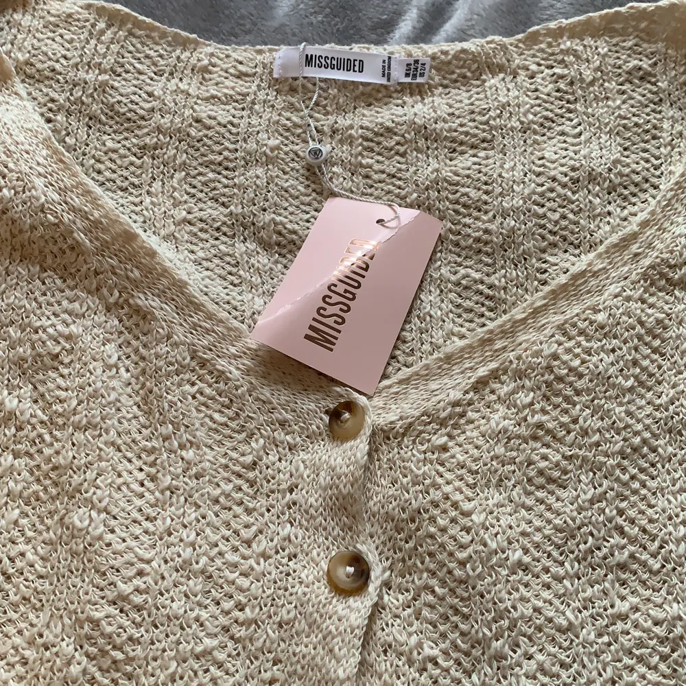 Detta är en beige off-shoulder stickad tröja med knappar. Jättefin och skönt matrial. Oanvänd med prislappen kvar. Köpt för 300kr😊. Stickat.