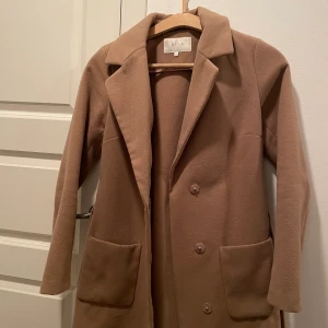 Beige kappa - Beige kappa från Vila i strl S, sitter till knäna på mig som är 178 cm. Är egentligen en M, så den sitter åt det tajtare hållet på mig. Varsamt använd. 