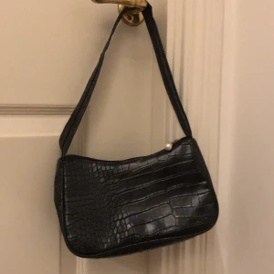 Svart handväska  - Trändig axelväska. Inte jättestor, med måtten 22x14, men med ganska mycket plats i. Gjord i konstläder. Väskan är ny men saknar prislapp💞