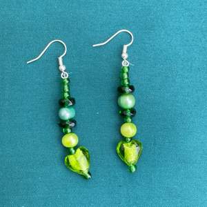 Handgjorda örhängen i gröna pärlor (glas & plast). Cirka 5,5 cm långa. Inte alls tunga. 