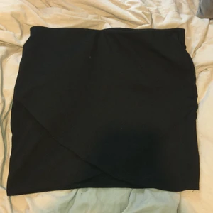 Kjol från Ginatricot  - En svart fin enkel kjol, med lite omlott längst ner av kjolen. Storlek L och kjolen är i stretchmaterial med resårband i midjan. Bekväm och enkel. Endast använd 1-2 gånger. Vid leverans står köparen för frakten. 