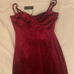 Röd midiklänning i sammet strl M - ”Velvet cup midi dress”. Färg: wine. Storlek: M. Aldrig använd, etiketten är kvar. Sitter tight men tyget är stretchigt så det blir inte obekvämt. Väldigt fin, går ungefär till knäna 