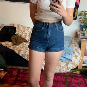 American Apparel jeans-shorts - Ett par högmidjade jeansshorts i en mörkblå färg. Väldigt små på mig, därav sitter de lite konstigt på bilden. Otroligt fina annars. Sparsamt använda, så mycket fint skick. Storlek 25 i jeans, skulle säga att de är som en 34/xs