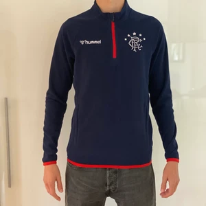 Hummel Fleecetröja Strl:S - Detta är en fleecetröja ifrån Hummel med fotbollslaget Glasgow Rangers tryck på. En skön och mysig tröja man både kan träna i och använda i andra olika tillfällen.