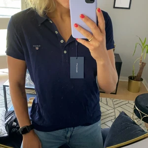 Kortärmad piké från GANT - Kortärmad piké från GANT. Mörkblå. Storlek L. Dammodell. Nypris 650 kr. Oanvänd med tag kvar!