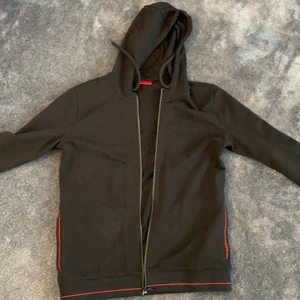 Hugo boss hoodie  - Säljer en svart röd Hugo boss hoodie i storlek L, inköpt från boozt, nypris 1200kr säljer för 500kr. Använd en gång och är i mycket bra skick (otvättad) pris kan diskuteras. Köparen står för frakt.