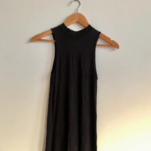Svart kortklännig - Svart kortklänning som gick till mitten av låret på mig. Plagget har en låg polokrage och är i ett tunt flowy material, i XS