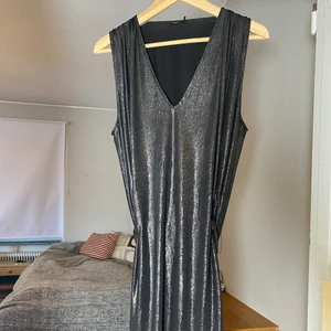 Filippa K klänning - Svart Silvrig klänning med fint fall. Passformen ger en fin form. Ett band som stramar åt i midjan annars lös passform. Osäker på Nypris men 1000-2000 kr. Perfekt nyårskläning. Strl L men jag är en M och den passar bra på mig.