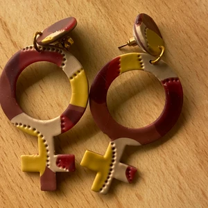 Venus örhängen i lera  - Ett par Venus örhängen i polymerlera , som gör att de blir lättburna pga mindre vikt för örsnibbarna. Superfin färgkombination med lila , beige och gul. Tyvärr används de inte såsom de borde.  Kan fraktas både spårbart och icke spårbart. 