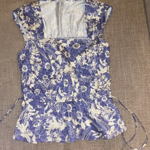 blå blus - säljer denna jättesöta blå blus med blommor och volang ifrån &other stories!💙 toppen har band vid sidan som man kan knyta söta rosetter vid sidan!💙 den är jättefin och köptes för 590kr och är endast testad men tyckte ej den passade på mig!💙 jag säljer för 290kr+frakt!💙