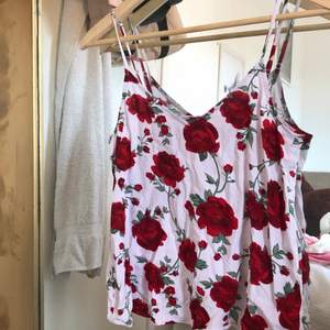 ett vitt linne med röda rosor på, jättegulligt! skönt tyg och perfekt till sommaren! fråga om ni undrar något, köparen står för frakten:) 