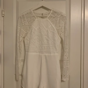 Vit playsuit - Vit playsuit från Nelly med öppen rygg och spets på överkroppen. Storlek S, använd 1 gång. Priset är inklusive frakt! 