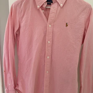 Ralph Lauren dam skjorta  - Ralph Lauren dam skjorta i rosa färg. Super slim fit i storlek 6, vilket motsvarar xs/small . Liten färg fläck på armen. Ord pris 1200 kr