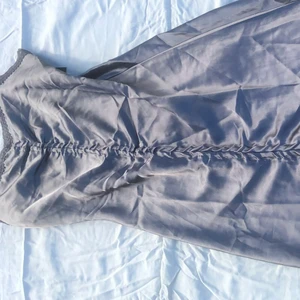 Siden klänning  - Fin sides klänning med axelband, spest detaljer över bröstet och detaljer längst klänningen. Storlek 38, grå i färgen och spetsen lite mörkare grå. Aldrig använd.