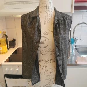 Vintage väst i metallic/guld, S - Väst i storlek S som skimrar i guld/metallic. Väldigt retro.   Det går bra att både hämta upp den på Södermalm i Stockholm eller skickas mot frakt, samfraktar självklart vid köp av flera annonser. Jag ansvarar ej för postens slarv men föredrar spårbar frakt för bådas skull, lycka till!