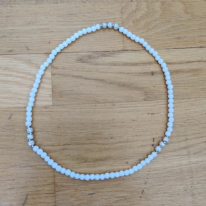 Halsband med kulor - Ett halsband från Glitter som inte kommit till användning, har dock använts någon gång eller blivit testad. Vita lite matta kulor och glittriga silver kulor. Inte jättelångt inte jättekort heller. (Köparen står för frakten)