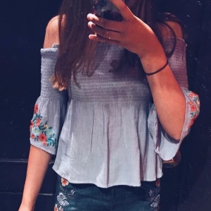 Hollister blus strl S - Gullig blus från Hollister. Endast använd en gång. Broderi på ärmarna, samt vida, sneskurna ärmar i slutet. Säljer pga för liten (bilden är gammal). Köparen står för frakten.