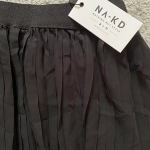 Veckad kjol - Säljer min svarta veckade kjol från na-kd som är helt oanvänd med prislappen kvar! 