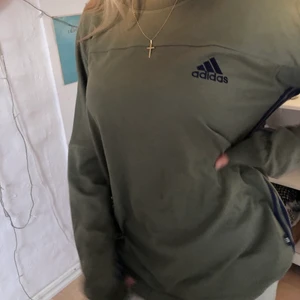 Grön Adidas sweatshirt - Säljer min as snygga sweatshirt från adidas som jag köpt på humana för 200kr! Strecken är på insidan armen vilket jag tycker gör den fetare. Sitter som en M/L