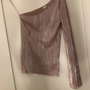 Topp med en ärm strl XS - Skimrig ljusrosa topp med en ärm från Gina. Köpare står för frakt